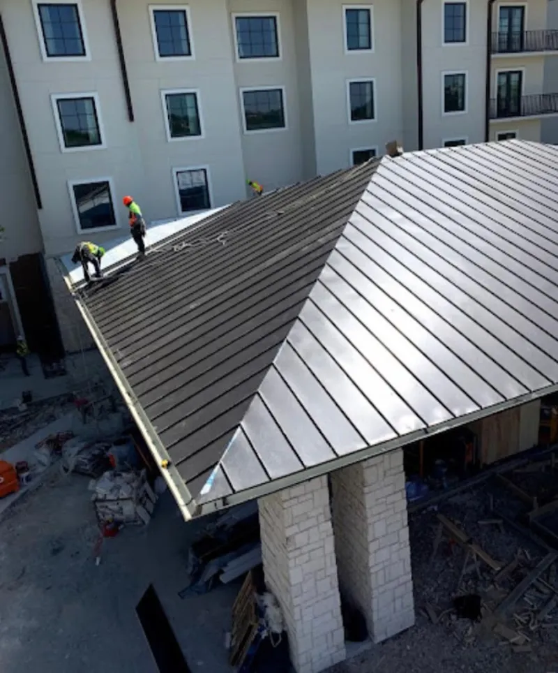 Crew installing standing seam metal roof panels on a commercial project in Peninsula